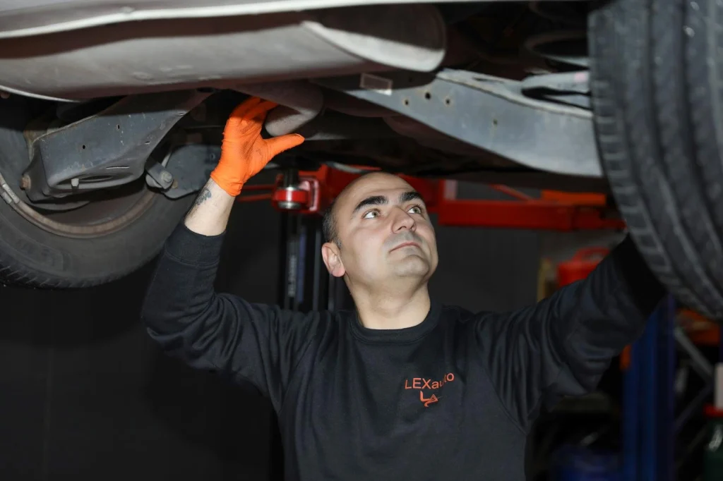 One of the owners of Lexauto Madrid working beneath a car on a lift.